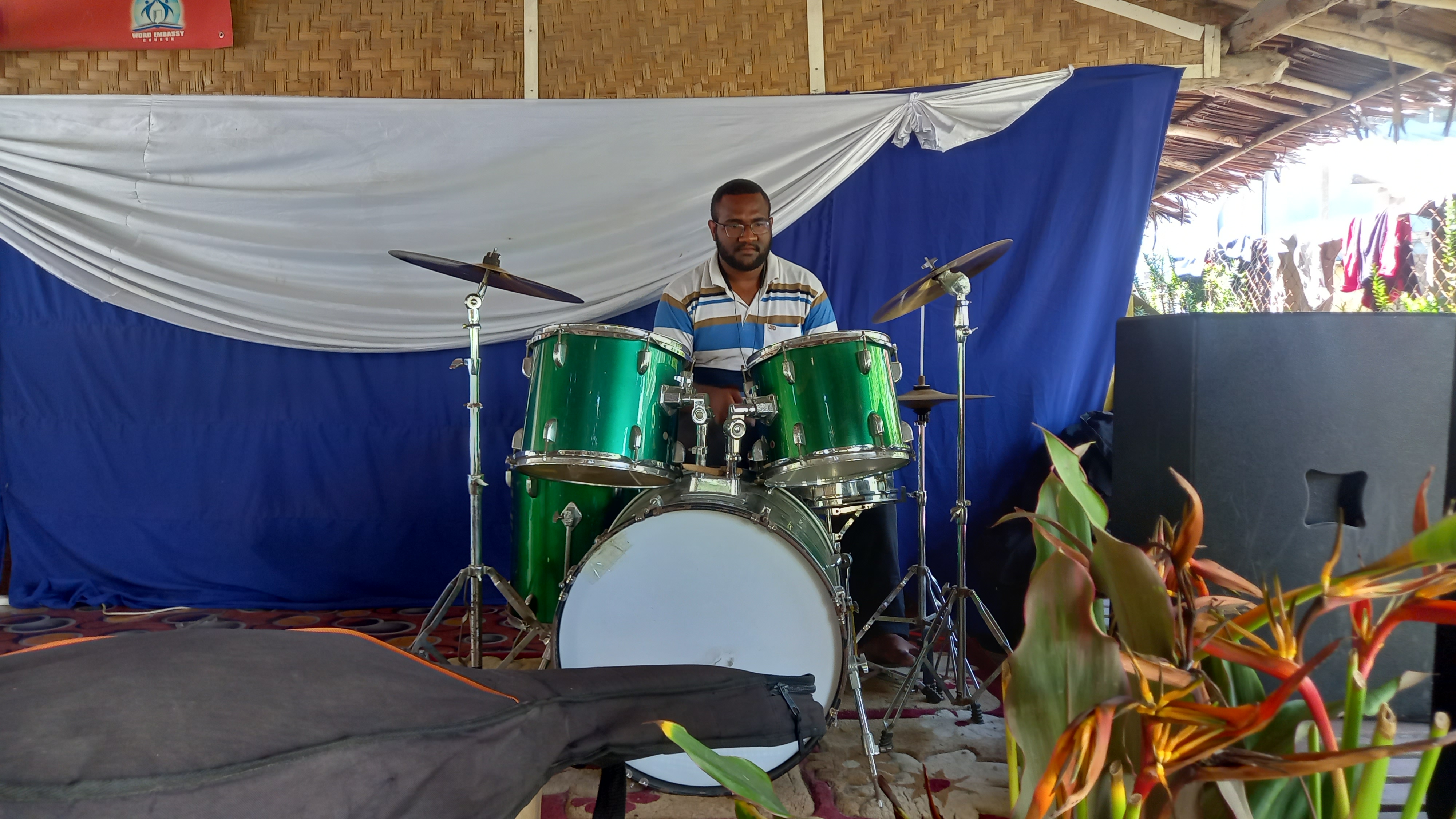 image of joshua junior kingal playing a green drumset